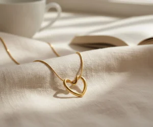 Gold heart pendant necklace resting on soft white fabric.